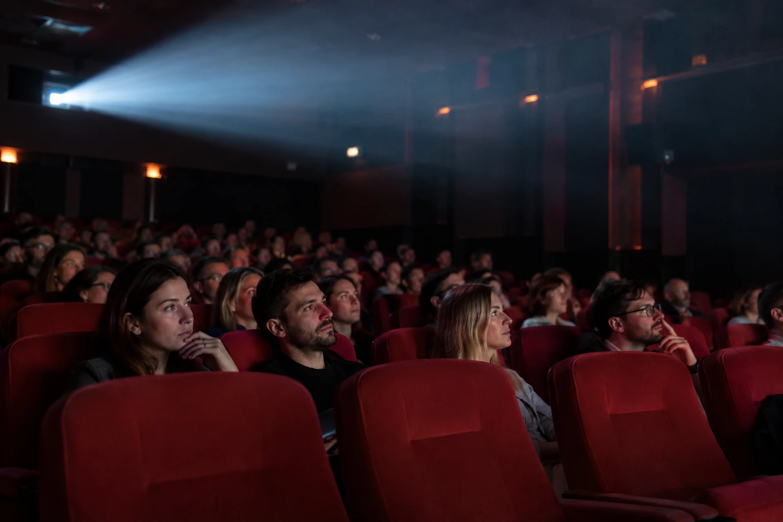 Kino dvorana s crvenim sjedalima i snopom svjetla projektora